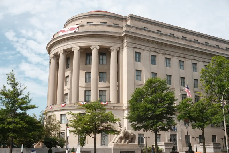 The columned facade of the Apex Building curves beneath a cloudy sky.