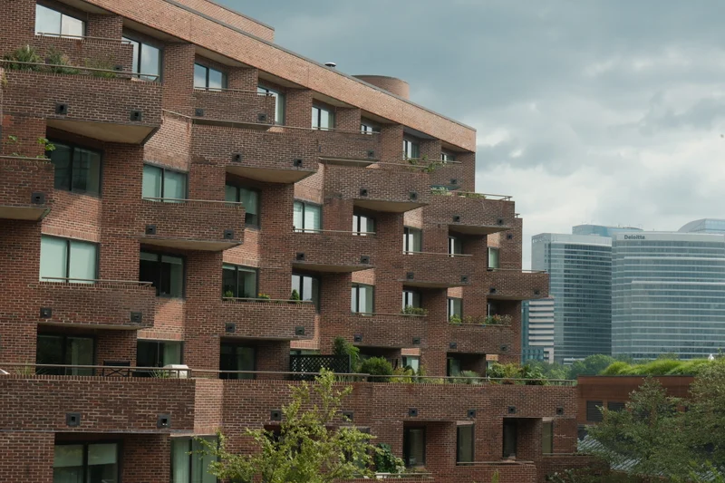 Terraced brick balconies dotted with plants form a stepped pattern against the city skyline.